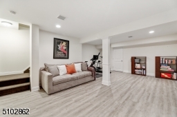 Finished lower level featuring carpeted stairs, new premium vinyl grey wood look floors, recessed lights, storage under the stairs, and a large storage / utility area