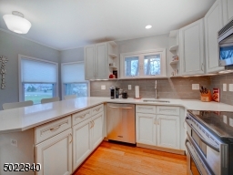Kitchen with off-white cabinets, stainless appliances, quartz counters