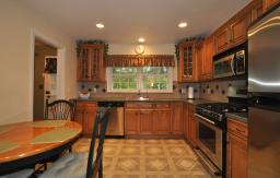 Eat-in kitchen with honey-hued custom cabinetry and stainless steel appliances.